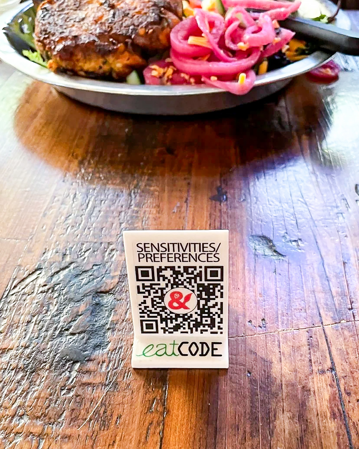 EatCode QR stand with plated food in a restaurant